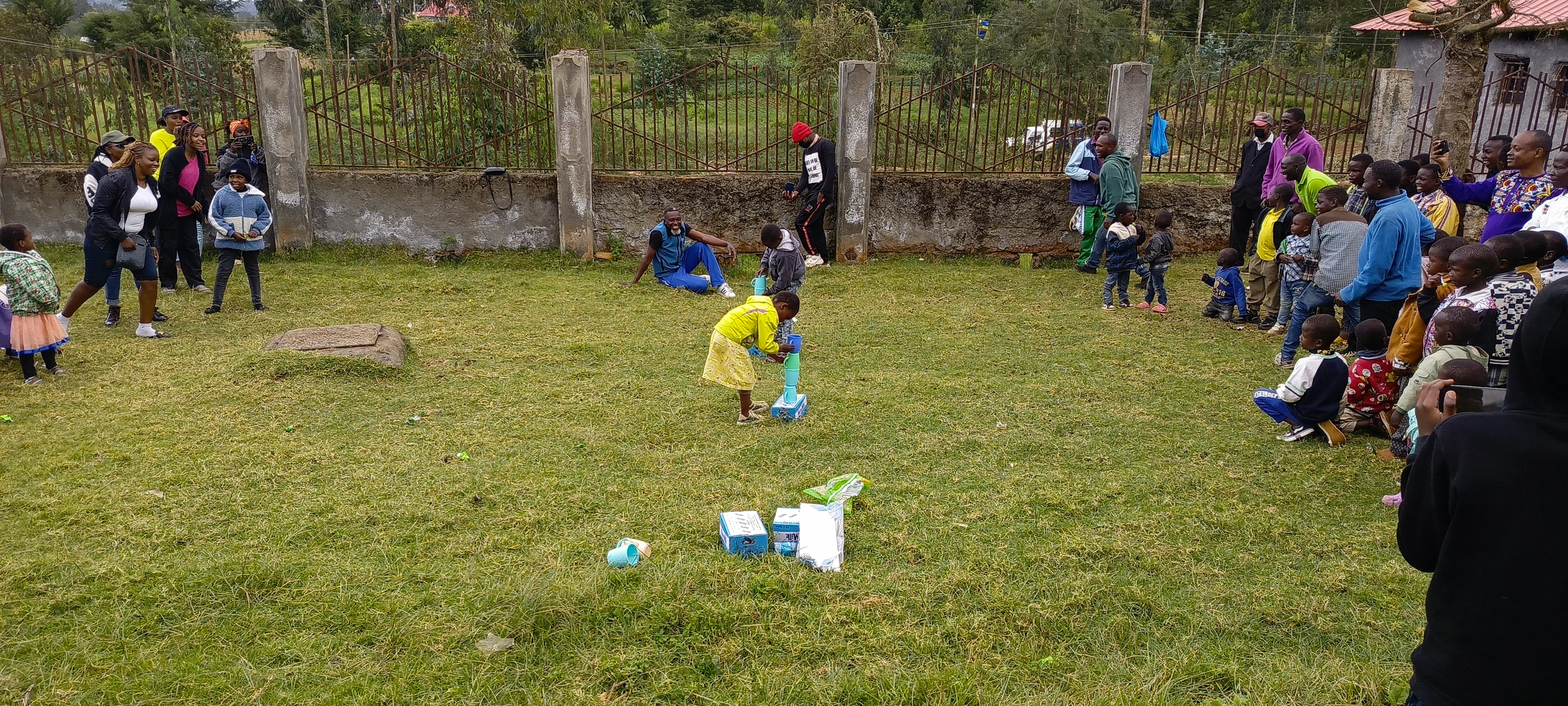 Children and visitors play a cup-stacking game on the lawn at Bethesda Child Care Centre in Mirangine